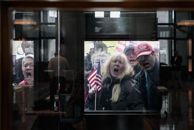 Protesters stand outside the Statehouse Atrium where reporters listen during the State of Ohio's Coronavirus response update on April 13, 2020 at the Ohio Statehouse in Columbus, Ohio. About 100 protesters assembled outside the building during Gov. Mike DeWine's weekday update on the state's response to the COVID-19 pandemic, upset that the state remains under a Stay-At-Home order and that non-essential businesses remain closed. (Joshua A. Bickel, Columbus Dispatch via USA TODAY NETWORK)