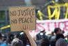 1200px-A_demonstrator_holds_a_No_Justice_No_Peace_sign_at_the_rally_for_Philando_Castile_outside_the_Governor's_residence_in_St_Paul_MN_7-7-2016_(28137456646).jpg